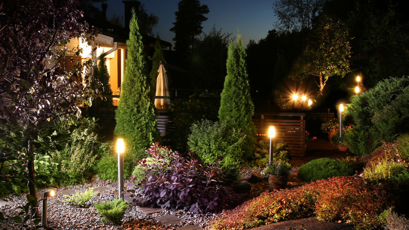 A garden at night with lit candles in the bushes